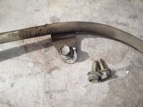 1990 Ford Taurus - A dirty sway bar and its mounting hardware lie on a concrete surface.