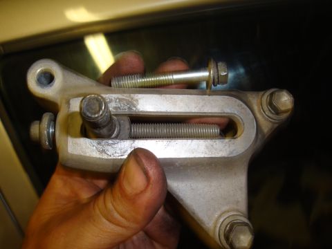 1990 Ford Taurus - A hand holds a metal bracket with a spring and bolts, likely a vehicle part.