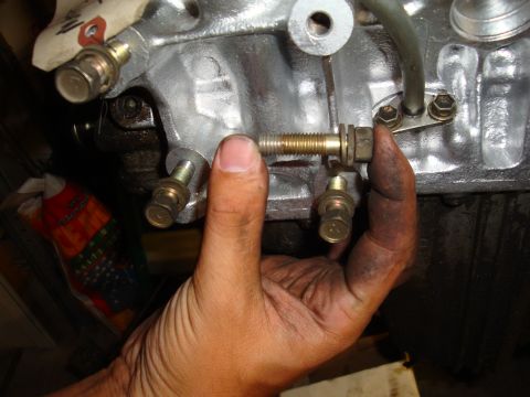 1990 Ford Taurus - Close-up of a hand manipulating a bolt on an engine part, showing mechanical detail.