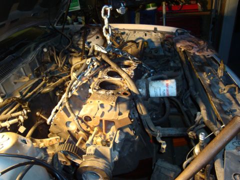 1990 Ford Taurus - The engine is partially disassembled, with a chain hoist attached, suggesting repair or maintenance work is underway.