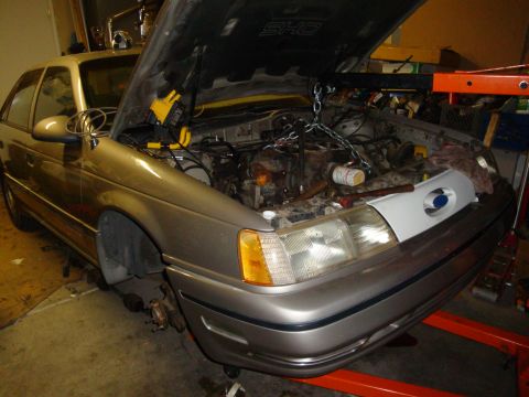 1990 Ford Taurus - A silver 1990 Ford Taurus is shown with its hood open, undergoing engine maintenance.