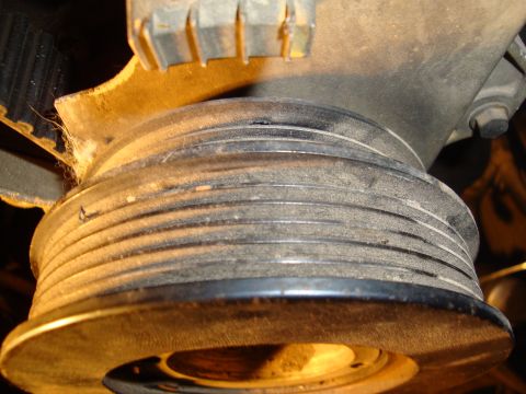 1990 Ford Taurus - Close-up view of a dusty engine pulley and belt system.