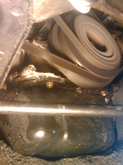 1993 Ford Bronco - Close-up view of engine belts and pulleys, with an oil pan in the foreground.