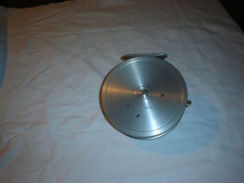 1990 Ford Bronco - A silver fishing reel with visible text is shown against a white background.