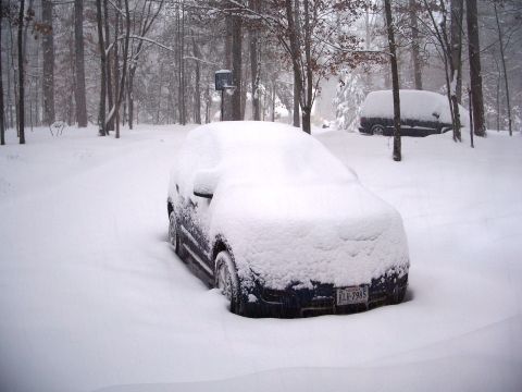 1971 Ford Ranchero - A dark blue car is almost completely covered by snow, with another vehicle visible in the background.