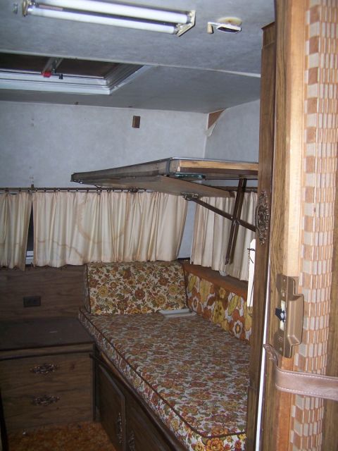 1974 Dodge RV/Conversion Chassis - The interior of an RV shows a bed area with floral cushions and cream-colored curtains.