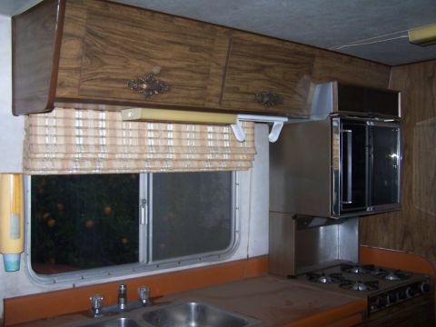 1974 Dodge RV/Conversion Chassis - Interior view of an RV kitchen wood cabinetry, a window with blinds, a double sink, and a gas stovetop.