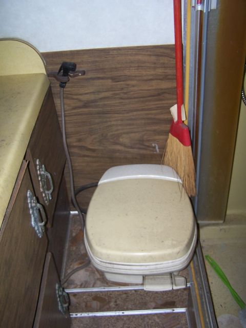1974 Dodge RV/Conversion Chassis - Interior shot of a toilet and broom in what appears to be an RV bathroom.
