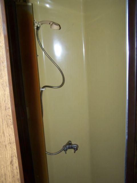 1974 Dodge RV/Conversion Chassis - Interior view of an RV shower stall, showing the shower head, faucet, and walls.