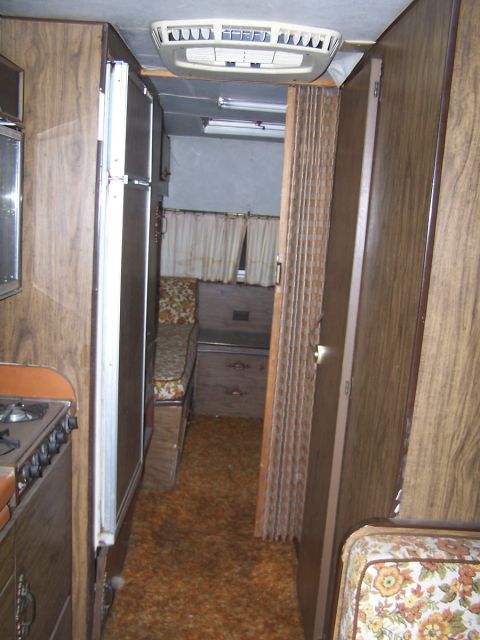 1974 Dodge RV/Conversion Chassis - Interior view of an RV with wood paneling, floral upholstery, and orange carpet.
