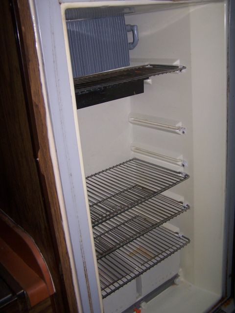 1974 Dodge RV/Conversion Chassis - The interior of a refrigerator with multiple wire shelves and a visible water stain on the lowest shelf.