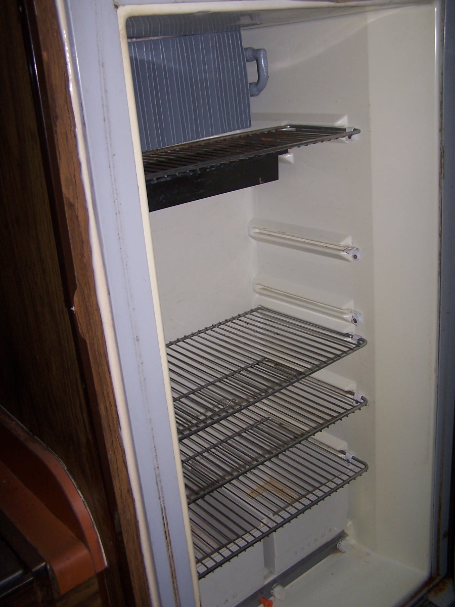 Refrigerator interior with wire shelves and cooling fins, showing a water mark on the bottom shelf