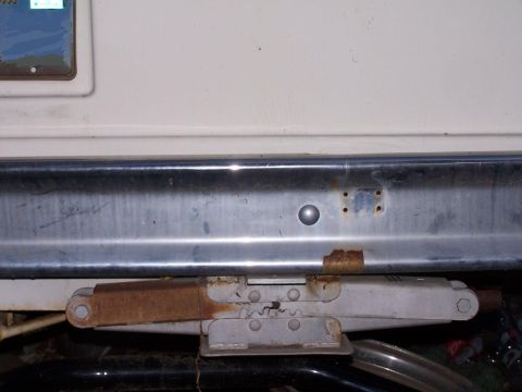 1974 Dodge RV/Conversion Chassis - Close-up of an RV's rear bumper and a scissor jack, showing signs of wear and rust.