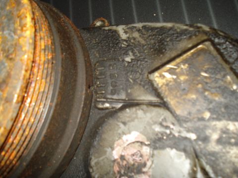 1991 Ford Bronco - A close-up view of a vehicle part, showing some stamped markings and significant rust and grease buildup.