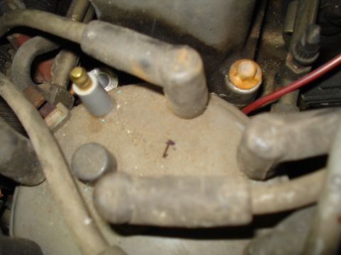 1991 Ford Bronco - Close-up of an engine distributor cap with visible spark plug wires and a small arrow marking.
