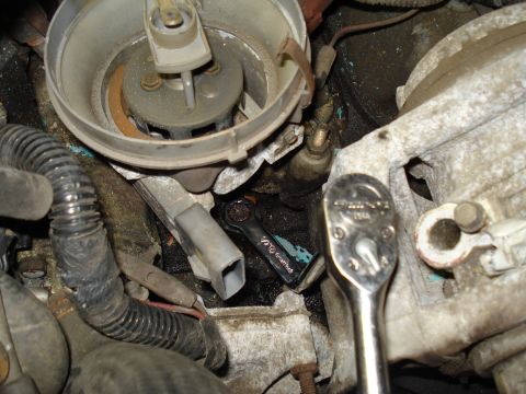 1991 Ford Bronco - Engine distributor cap and wires with a ratchet tool, likely during maintenance or repair.