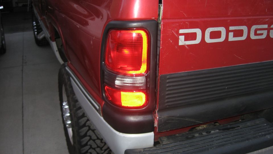 Red Dodge pickup truck rear quarter panel with taillight and tailgate visible