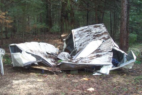1994 Ford F-150 - A severely damaged trailer lies in a wooded area, with the Supermotors.net logo visible in the lower right corner.