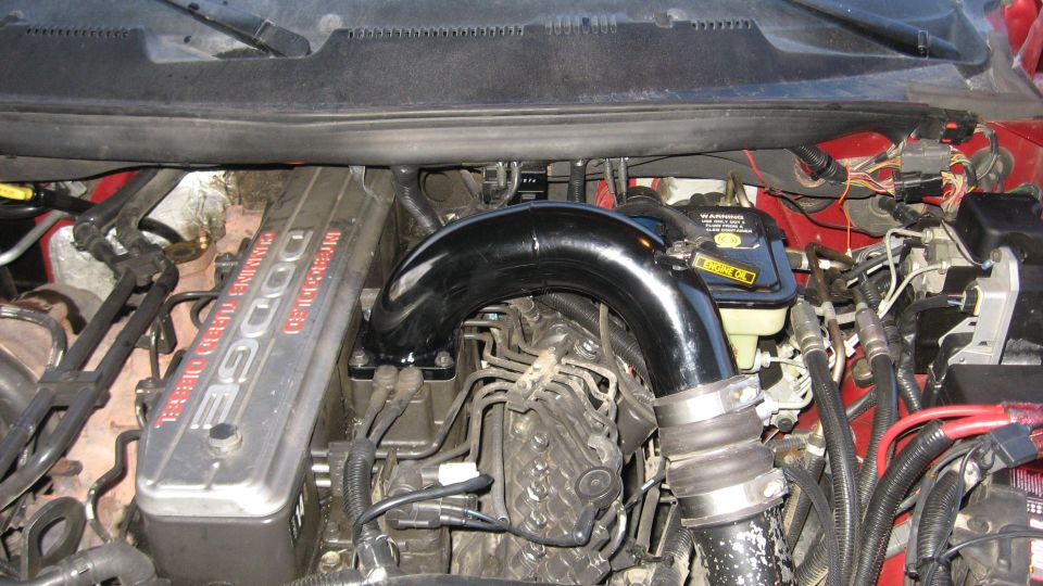 Dodge 5.9L Cummins Turbo Diesel engine with aftermarket intake pipe. Shows engine block and some wiring