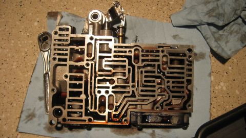 1997 Dodge 2500 - A transmission valve body, disassembled and resting on a blue shop towel next to a ratchet, shows intricate internal passages.