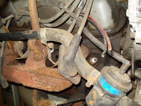 1991 Ford Bronco - Close-up of engine components including hoses, wires, and a spark plug. A blue label is visible.