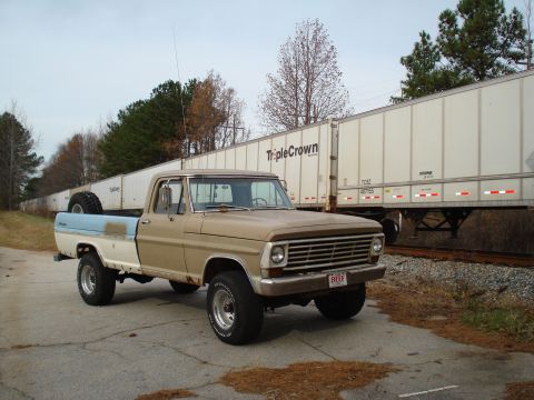 1967 Ford F-250 - A two-tone Ford F-Series truck is parked next to a long train car with 'Triple Crown' branding.
