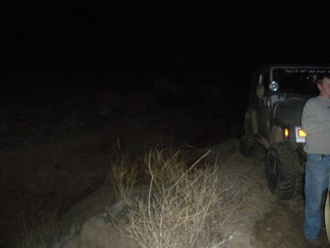 1990 Ford Bronco - A Jeep Wrangler is parked on a dirt path at night, with a person standing beside it.
