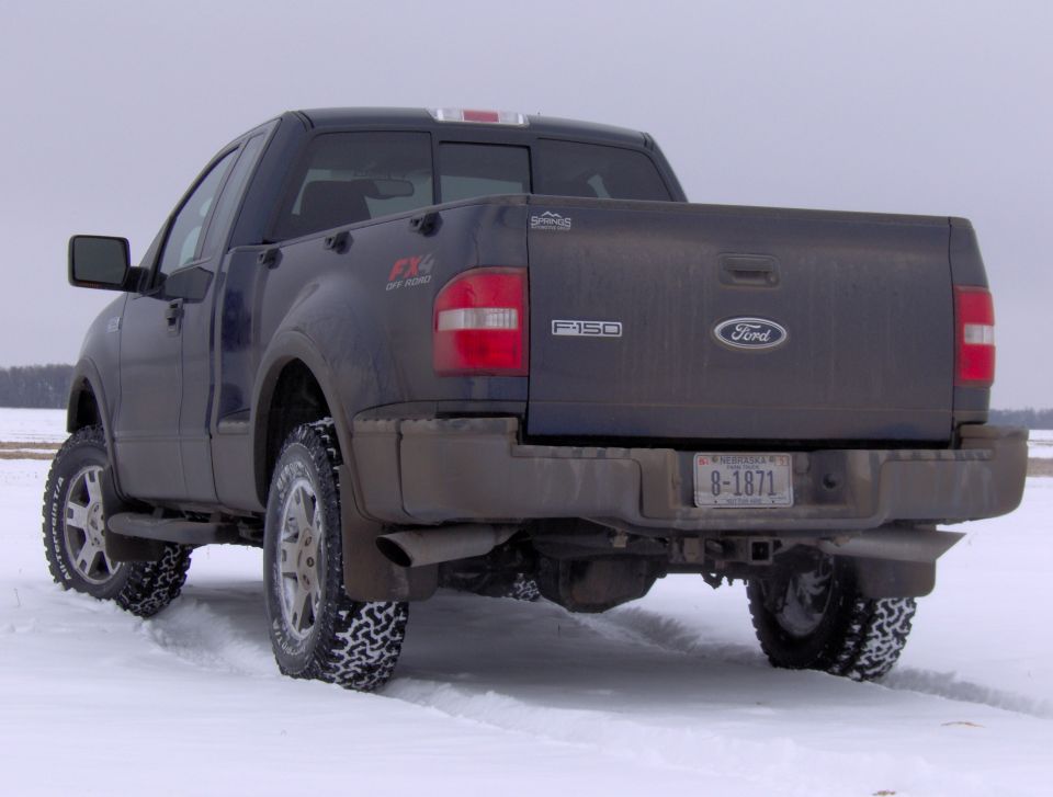 Gray Ford F-150 FX4 pickup, rear three-quarter view, parked in snow