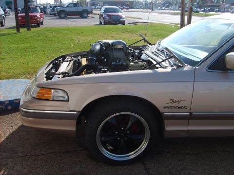 1993 Ford Crown Victoria - 1993 Ford Crown Victoria with its hood open, revealing the engine bay. The 'Sport' trim is visible on the fender.