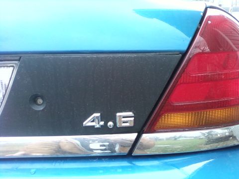1998 Ford Crown Victoria - The rear of a blue vehicle shows a '4.6' badge and chrome trim.