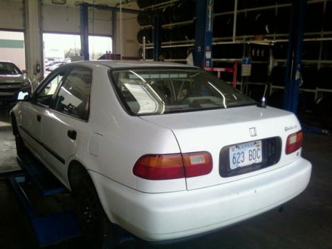 2000 Mercury Grand Marquis - A white sedan is parked on a lift inside a garage, with another vehicle visible in the background.