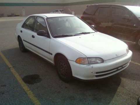 2000 Mercury Grand Marquis - A white sedan is parked in a lot next to a dark SUV. There is a dark stain on the asphalt in front of the car.