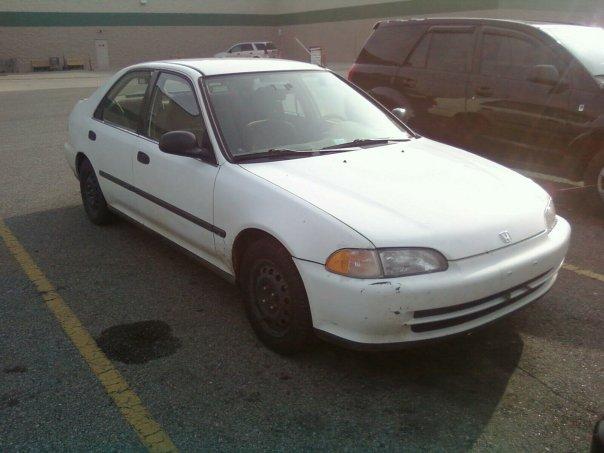 white sedan parked in a lot, dark SUV next to it