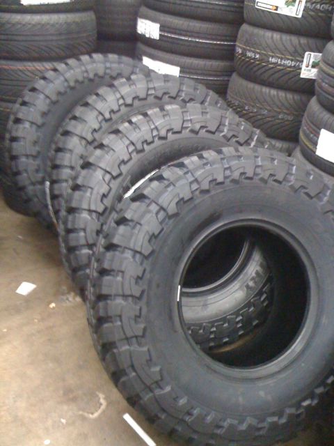 1996 Ford C-350 (Centurion Conversions) - A stack of four aggressive tread off-road tires are displayed in a retail setting.