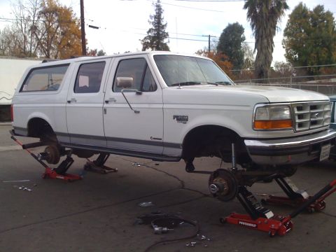 1996 Ford C-350 (Centurion Conversions) - This white Ford Bronco Centurion Conversion SUV is lifted on jacks, with its wheels removed for service.