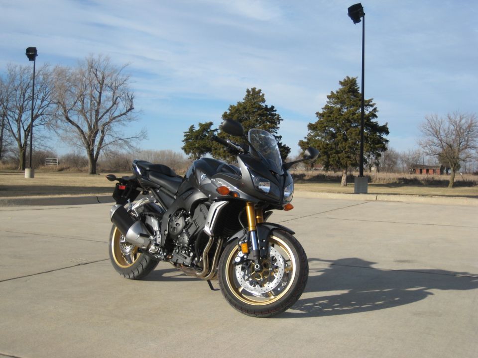 Dark gray Yamaha FZR1000 motorcycle with gold wheels parked on concrete