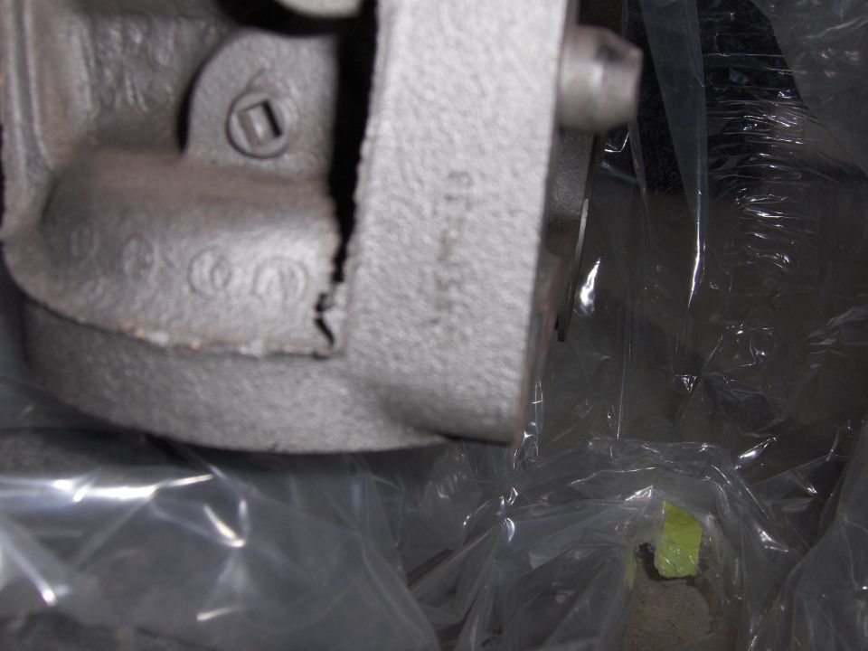 Cast metal part with stamped numbers, possibly a brake caliper or engine component