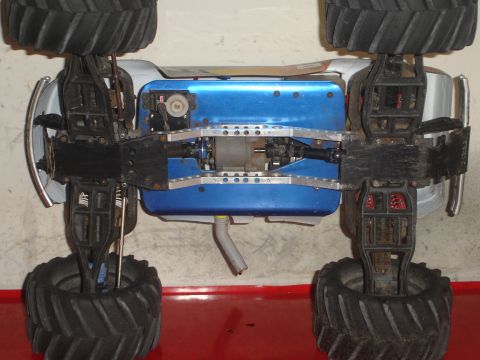 1989 Ford Bronco - Underside view of an RC monster truck chassis with blue bodywork and exposed mechanical components.