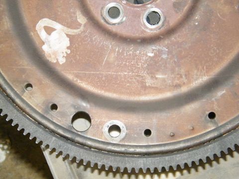 1982 Ford Bronco - This image shows a close-up of a rusty flywheel, a component of a vehicle's engine.