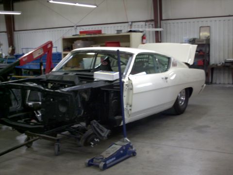 1963 Ford Fairlane - White coupe in garage with front end disassembled, undergoing repairs or restoration.