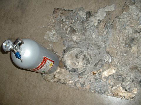 1963 Ford Fairlane - A silver nitrous oxide bottle lies beside a heavily damaged engine block on a concrete surface.