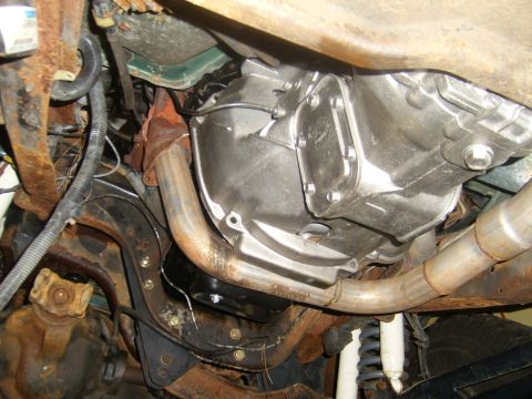 1994 Ford Bronco - The underside of a vehicle shows the transmission and exhaust system, with significant rust on the frame components.