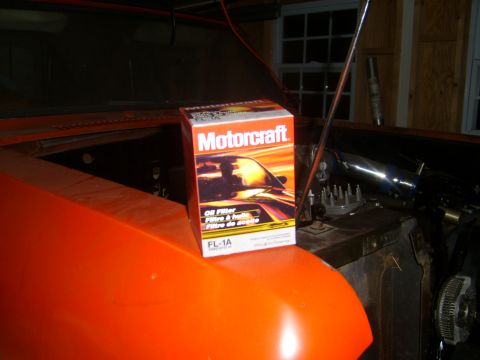 1994 Ford Bronco - A Motorcraft oil filter box rests on the fender of an orange vehicle with its hood open.