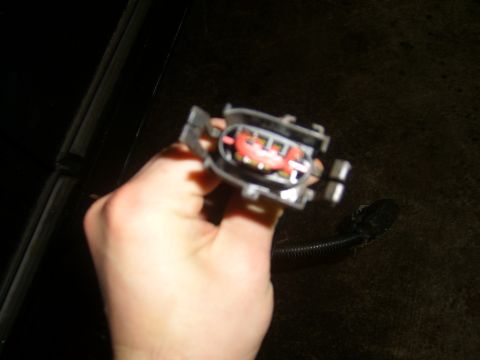 1994 Ford Bronco - Close-up of an electrical connector with visible terminals being held by a hand.