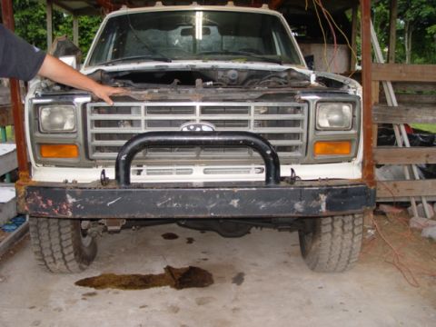 1996 Ford Bronco - Front view of a white truck, likely from the 1980s, with its hood open and a black bull bar attached to the bumper.