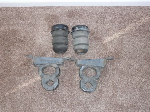 1988 Ford Bronco - Two rear bumperettes and their metal mounting brackets are shown laid out on a carpeted surface.