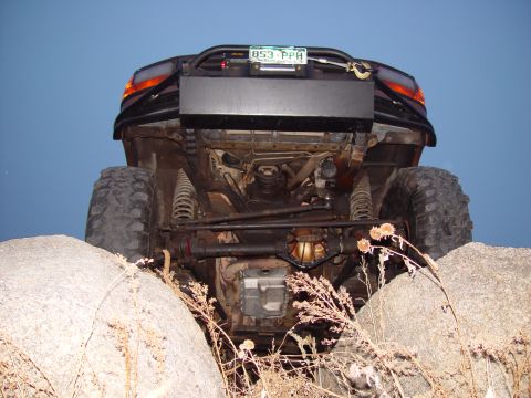 1993 Ford Bronco - This modified off-road vehicle is seen from the rear, with its undercarriage exposed as it navigates rocky terrain.