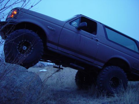 1993 Ford Bronco - This Ford Bronco is navigating rough terrain, with one wheel lifted off the ground.