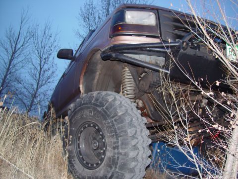 1993 Ford Bronco - Modified 1992 Ford Bronco with large tires and suspension components visible, parked in a dry, grassy area.