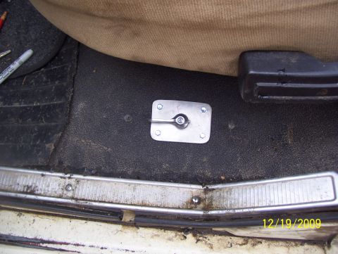 1978 Ford Bronco - Close-up of a vehicle's interior floor showing a metal mounting bracket and part of a seat.